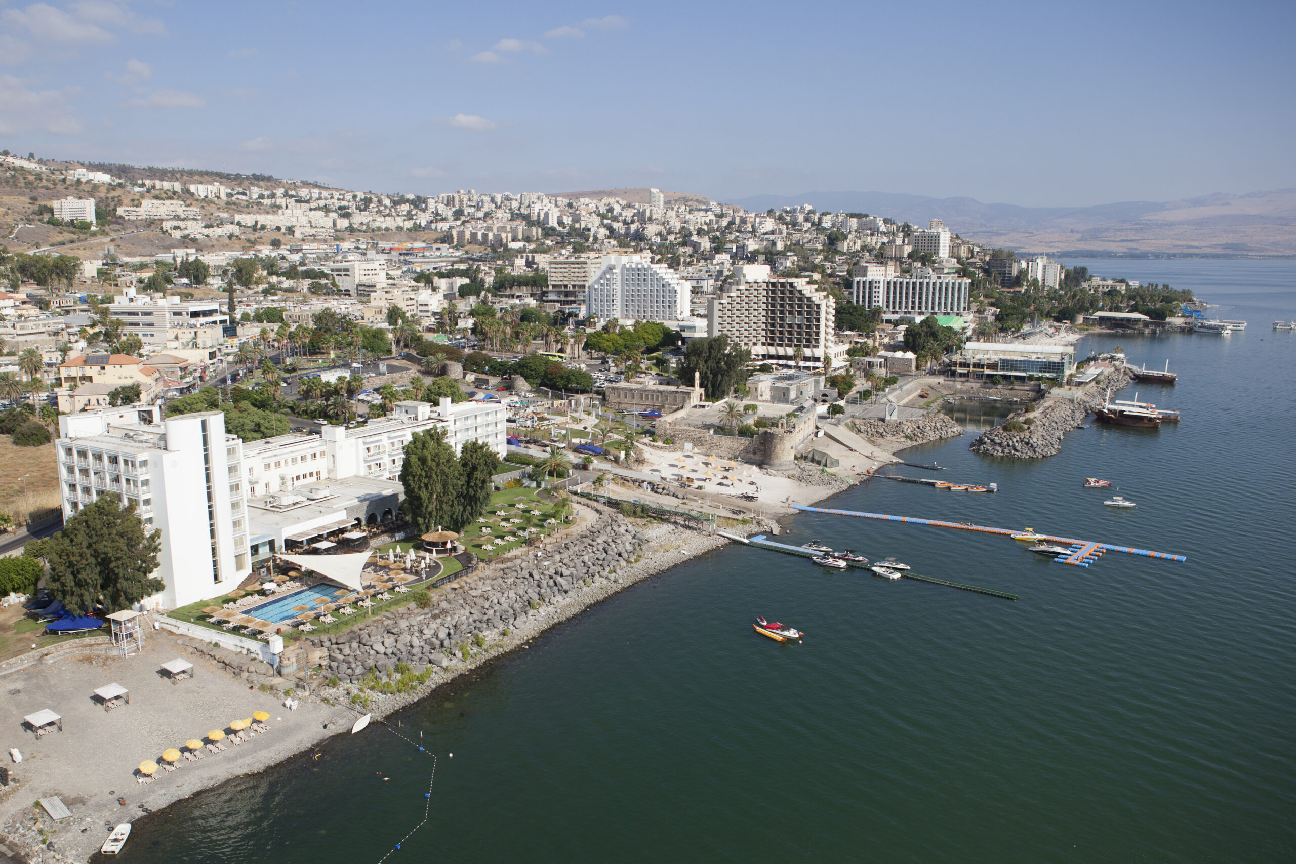 Tiberias  is a city on the western shore of the Sea of Galilee in the Lower Galilee. Established in 20 CE, it was named in honour of the emperor Tiberius.Tiberias has been venerated in Judaism since the middle of the 2nd century CE and since the 16th century has been considered one of Judaism's Four Holy Cities, along with Jerusalem, Hebron and Safed.In the 2nd-10th centuries, Tiberias was the largest Jewish city in the Galilee and the political and religious hub of the Jews of Palestine. According to Christian tradition, Jesus performed several miracles in the Tiberias district, making it an important pilgrimage site for Christians. Tiberias has historically been known for its hot springs, believed to cure skin and other ailments, for thousands of years.The picture shows an aerial view of the city. Photo by Itamar Grinberg.